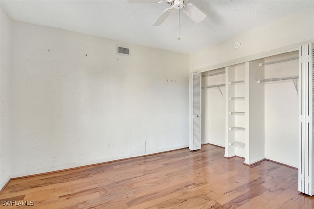 unfurnished bedroom featuring hardwood / wood-style flooring, a textured ceiling, ceiling fan, and a closet