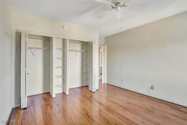 unfurnished bedroom featuring hardwood / wood-style floors, a textured ceiling, ceiling fan, and a closet