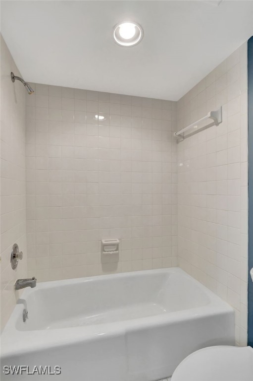 bathroom featuring tiled shower / bath and toilet