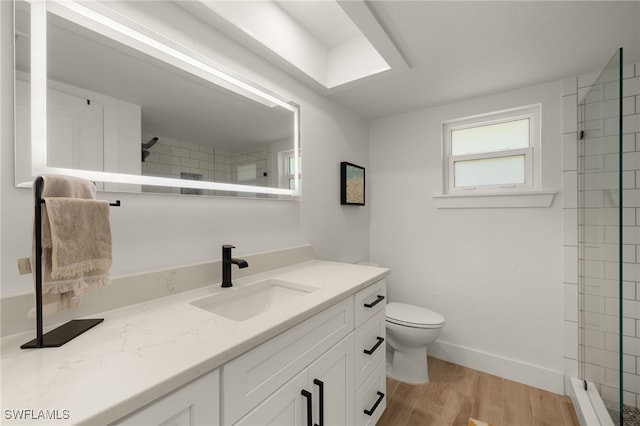 bathroom with toilet, hardwood / wood-style flooring, a tile shower, and vanity