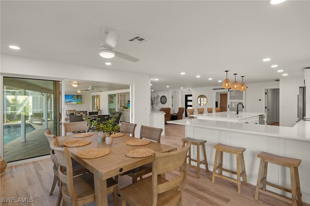 dining area featuring sink, light wood-type flooring, and ceiling fan