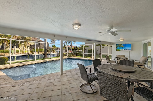 view of pool with ceiling fan, glass enclosure, and a patio area