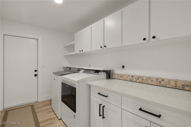 laundry room featuring cabinets, light hardwood / wood-style flooring, and washer and clothes dryer