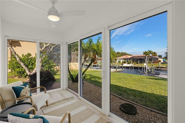 sunroom with a water view and ceiling fan