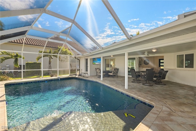 view of swimming pool with a patio, glass enclosure, and ceiling fan