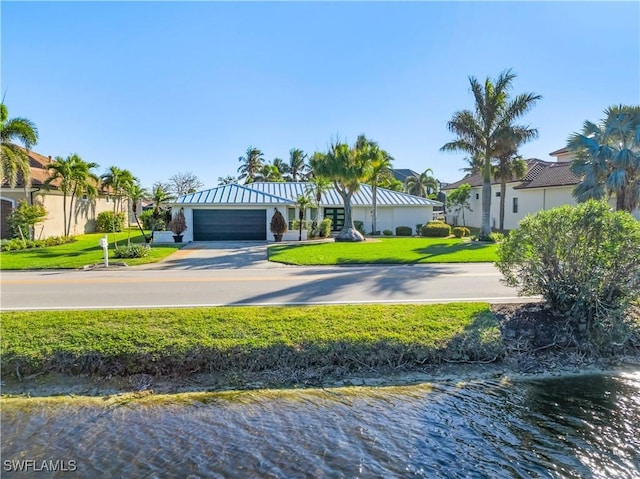 view of front of house featuring a garage, a water view, and a front lawn