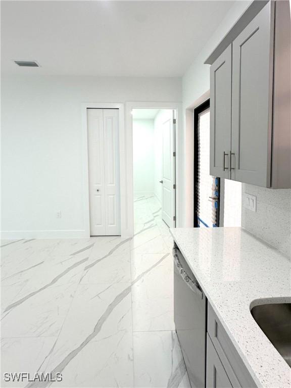 kitchen featuring light stone counters, sink, gray cabinets, and dishwasher