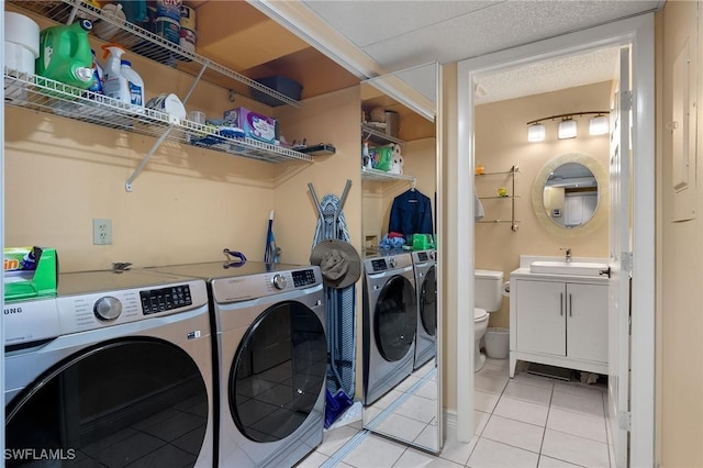 laundry room with light tile patterned floors, laundry area, separate washer and dryer, and a sink