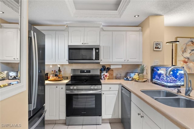 kitchen featuring stainless steel appliances, white cabinets, a sink, and backsplash