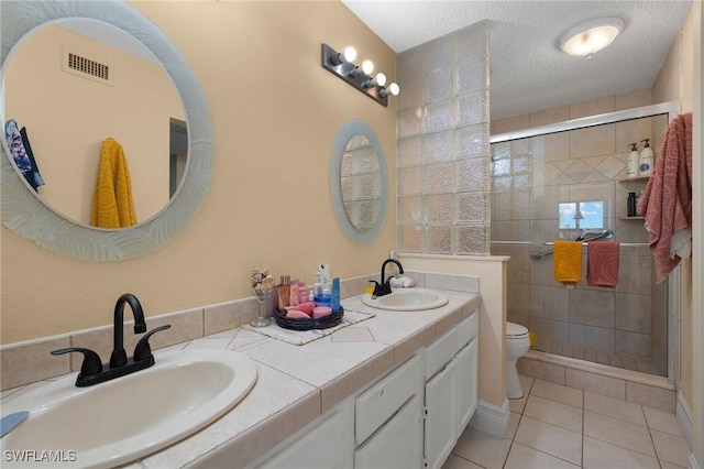 full bathroom featuring a textured ceiling, a sink, toilet, and a shower stall