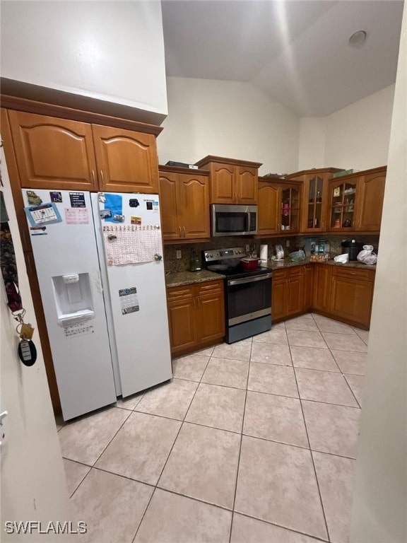 kitchen featuring decorative backsplash, light tile patterned floors, stainless steel appliances, and lofted ceiling