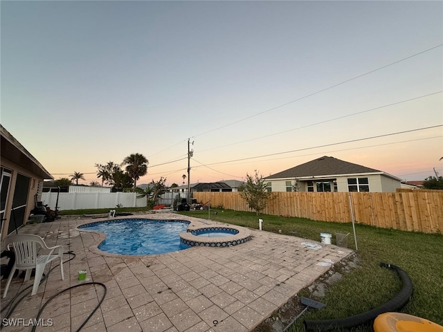 pool at dusk with a patio and an in ground hot tub