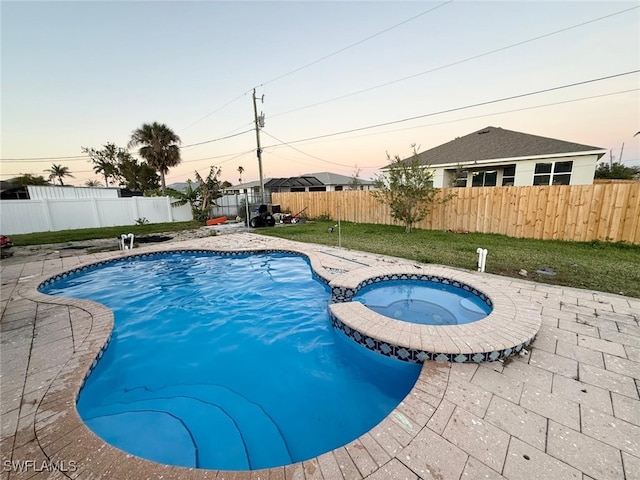 pool at dusk with an in ground hot tub and a patio area