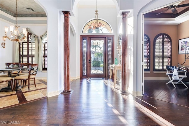 entrance foyer featuring dark wood-type flooring, a wealth of natural light, and ornate columns