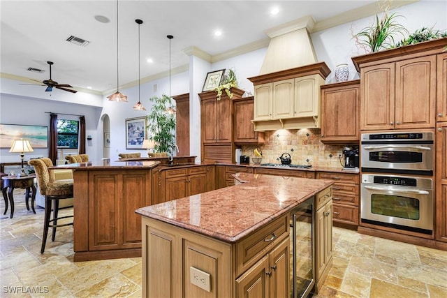 kitchen with pendant lighting, wine cooler, kitchen peninsula, stainless steel appliances, and light stone countertops