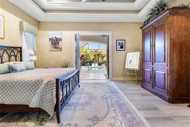 bedroom featuring ornamental molding, a raised ceiling, light hardwood / wood-style floors, and access to outside