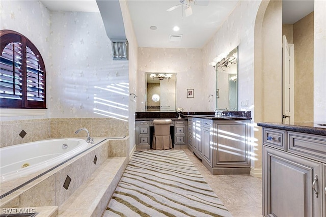 bathroom with vanity, tiled tub, tile patterned floors, and ceiling fan
