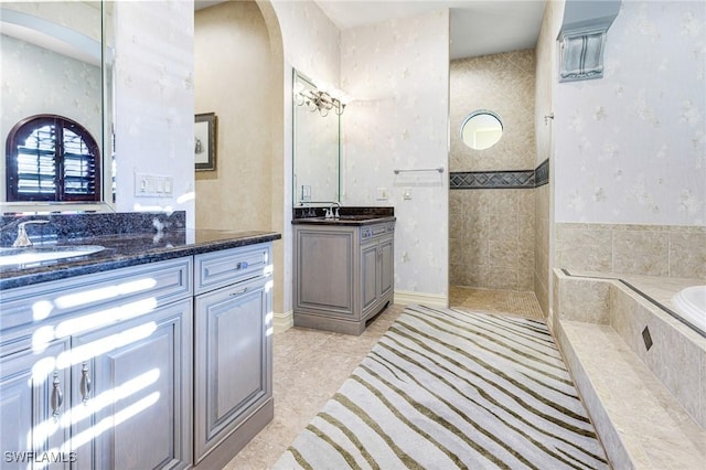 bathroom featuring tile patterned flooring, vanity, and tiled tub