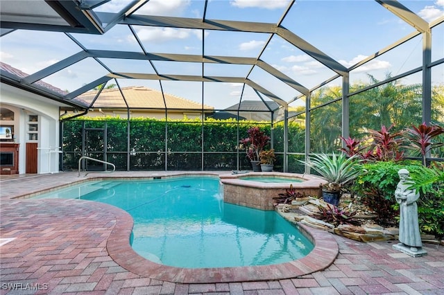 view of pool with a patio, glass enclosure, and an in ground hot tub