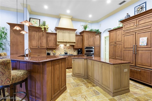 kitchen with a breakfast bar, appliances with stainless steel finishes, dark stone countertops, decorative light fixtures, and kitchen peninsula