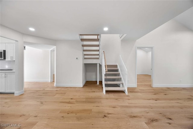 interior space featuring stairs, baseboards, light wood-style flooring, and recessed lighting