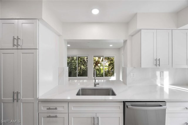 kitchen with recessed lighting, a sink, white cabinetry, light stone countertops, and dishwasher