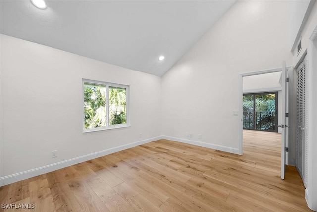 spare room with high vaulted ceiling, recessed lighting, light wood-style flooring, and baseboards