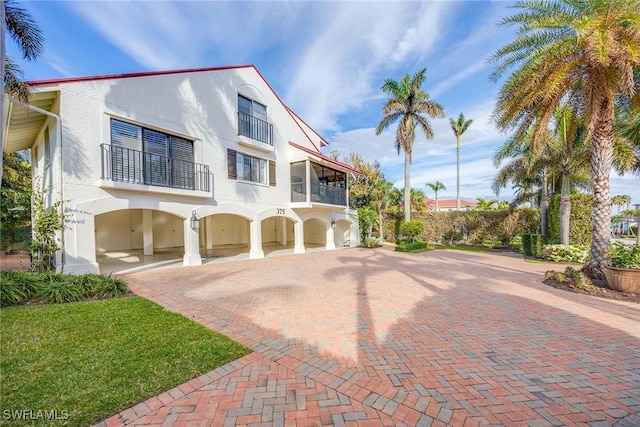 view of front of property with a balcony, driveway, and stucco siding