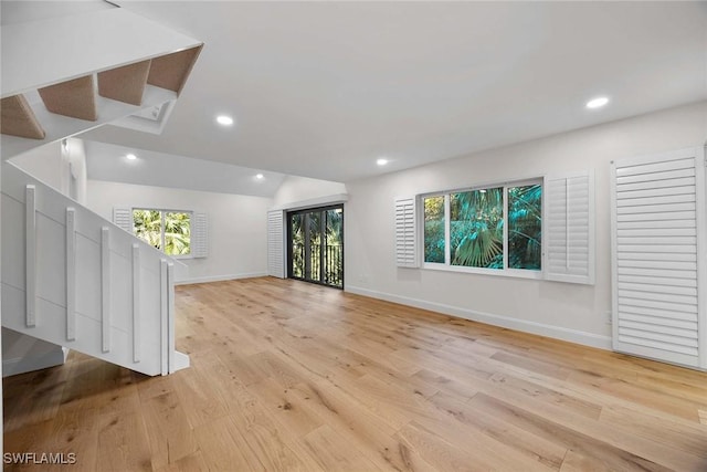 unfurnished living room with light wood-style floors, recessed lighting, lofted ceiling, and baseboards