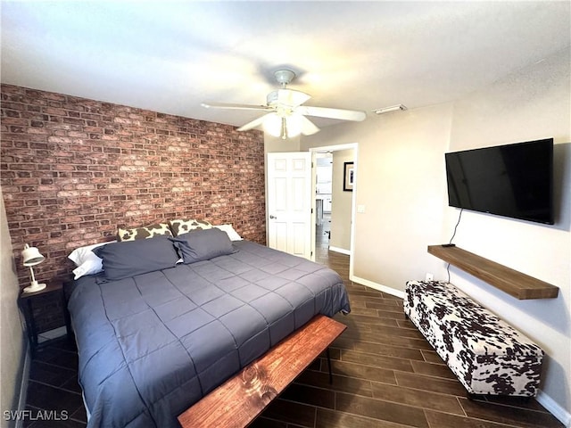 bedroom with ceiling fan and brick wall