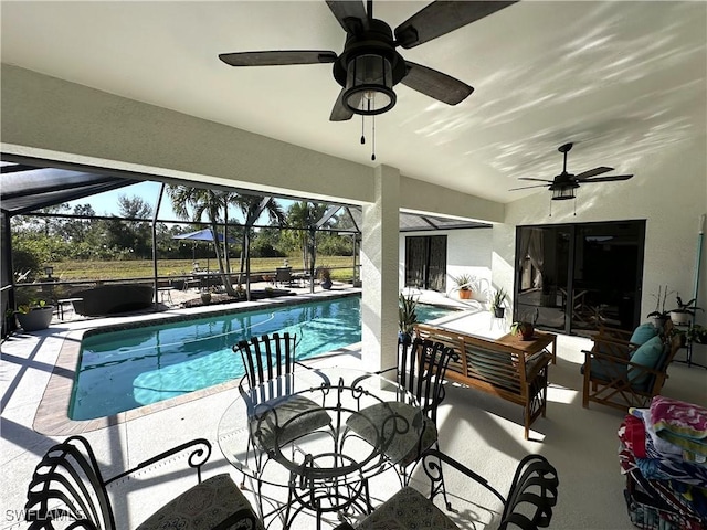 view of pool featuring ceiling fan, glass enclosure, and a patio area