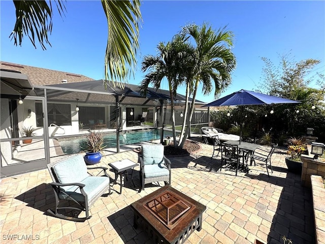 view of patio / terrace featuring a lanai, a fenced in pool, and a fire pit