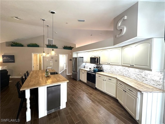 kitchen featuring pendant lighting, stainless steel appliances, an island with sink, and backsplash