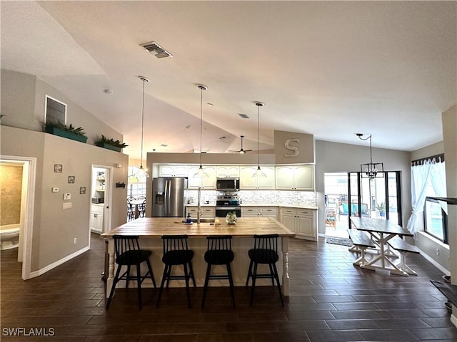 kitchen featuring tasteful backsplash, vaulted ceiling, a breakfast bar, and appliances with stainless steel finishes