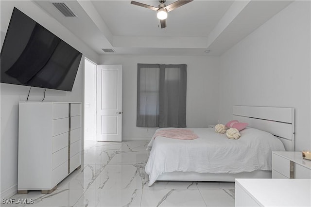 bedroom with ceiling fan and a tray ceiling