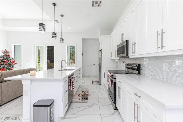 kitchen featuring hanging light fixtures, stainless steel appliances, sink, and a center island with sink