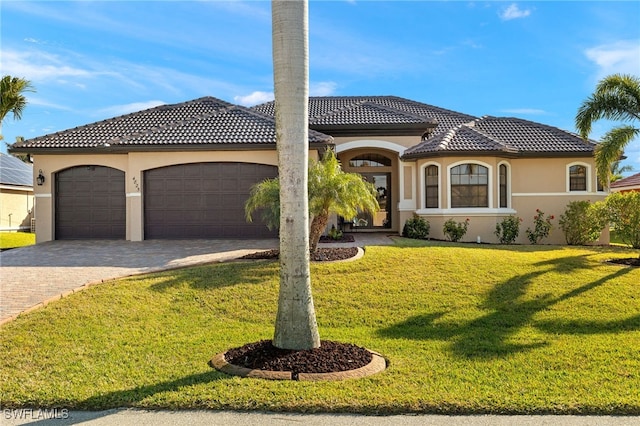 mediterranean / spanish home featuring a garage and a front yard