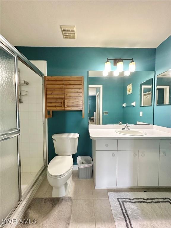 bathroom with tile patterned floors, vanity, toilet, and a shower with shower door