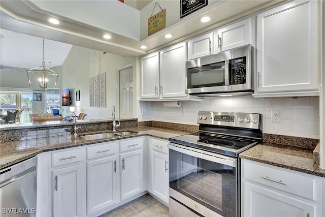 kitchen featuring dark stone countertops, stainless steel appliances, sink, and white cabinets