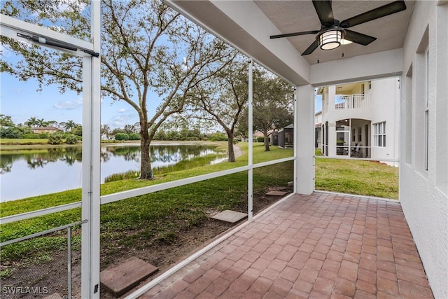 unfurnished sunroom with a water view and ceiling fan