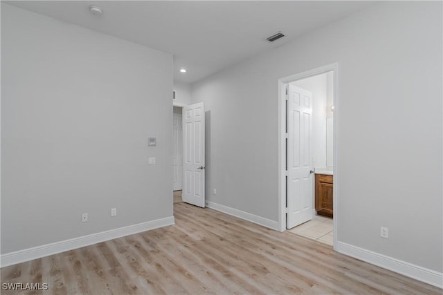 unfurnished bedroom with connected bathroom and light hardwood / wood-style flooring