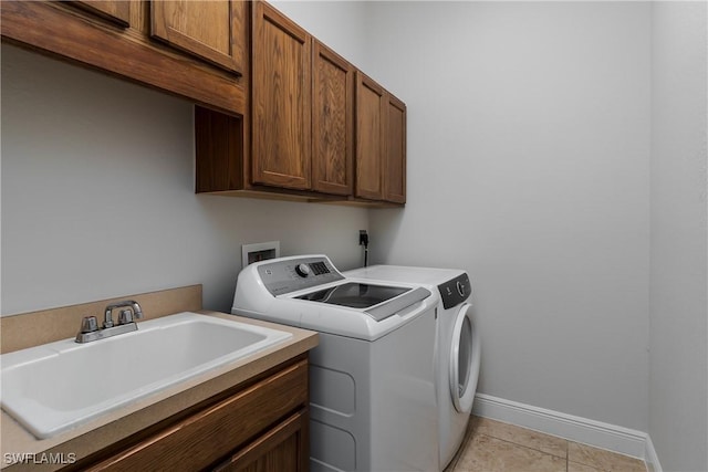 laundry area with sink, light tile patterned floors, washing machine and dryer, and cabinets