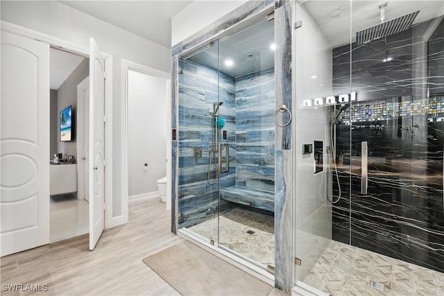 bathroom with hardwood / wood-style flooring, toilet, and an enclosed shower