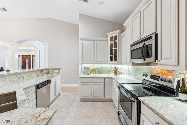 kitchen featuring light tile patterned flooring, lofted ceiling, appliances with stainless steel finishes, white cabinets, and backsplash