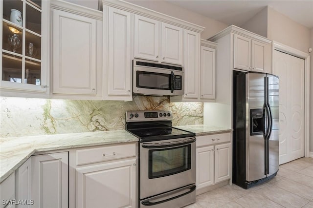 850 25th St SW, Naples, FL 34117 - kitchen featuring stainless steel appliances, light tile patterned floors, backsplash, and glass insert cabinets