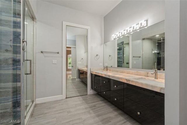 850 25th St SW, Naples, FL 34117 - bathroom with double vanity, wood finished floors, a stall shower, and baseboards