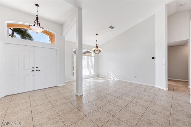 tiled foyer featuring an inviting chandelier and high vaulted ceiling