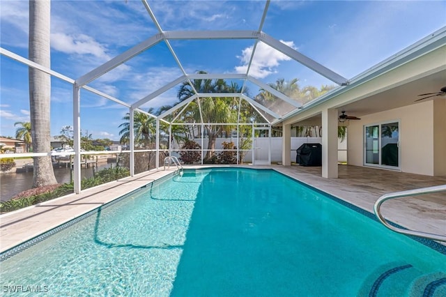 view of swimming pool featuring a water view, ceiling fan, a patio, and glass enclosure