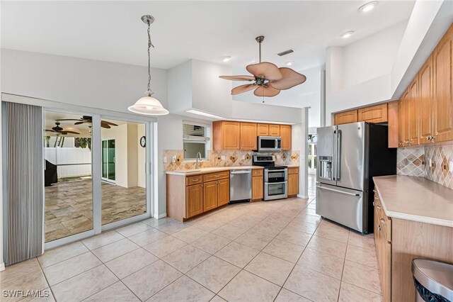 kitchen with light tile patterned flooring, decorative light fixtures, tasteful backsplash, sink, and stainless steel appliances