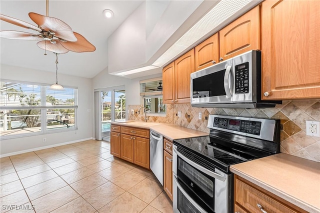 kitchen with appliances with stainless steel finishes, pendant lighting, tasteful backsplash, lofted ceiling, and sink